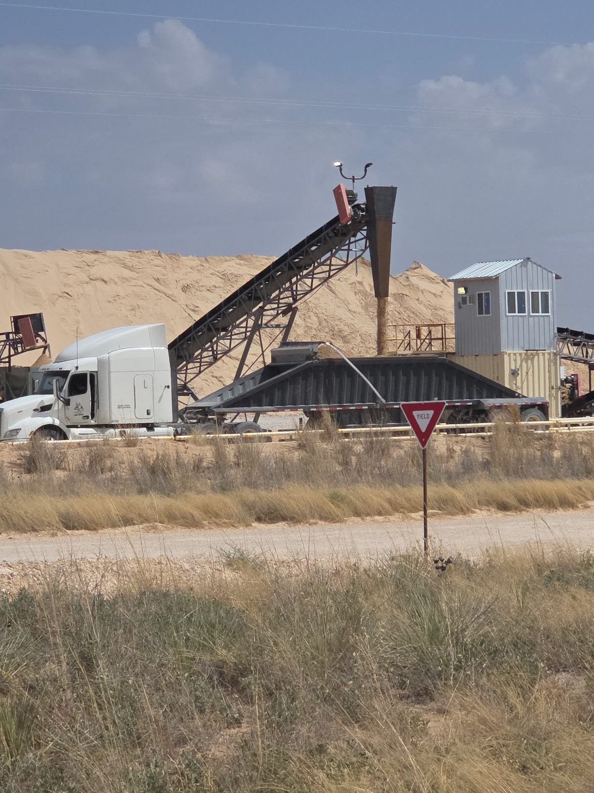Dump trailer being loaded with sand from a stacker conveyor at a sand plant