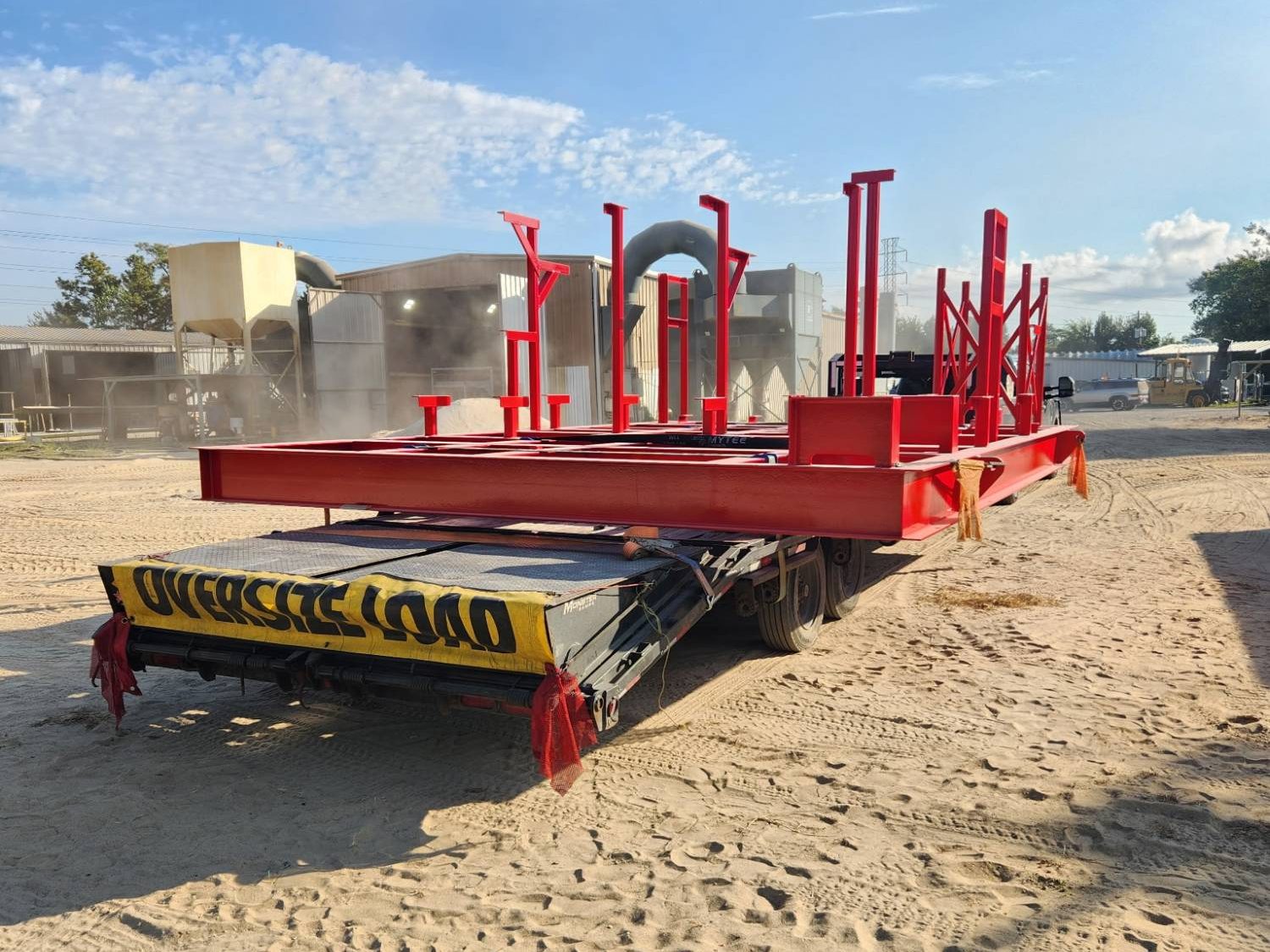Step-deck trailer hauling a large fabricated red structural steel frame