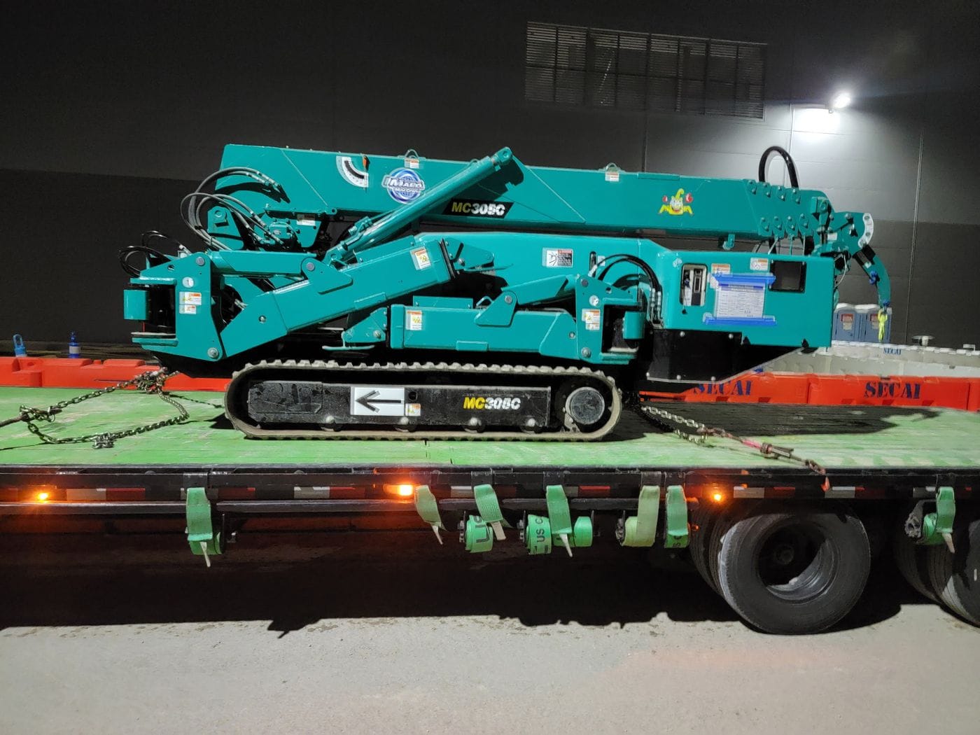 Flatbed trailer hauling oilfield equipment at night