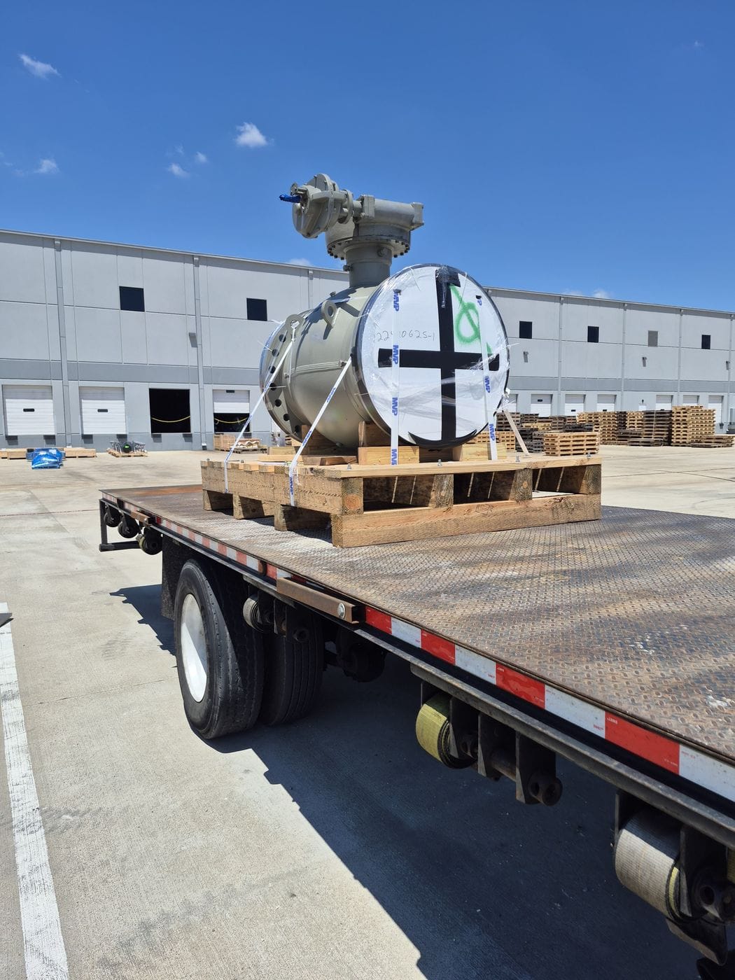 Flatbed trailer loaded with equipment at a warehouse dock