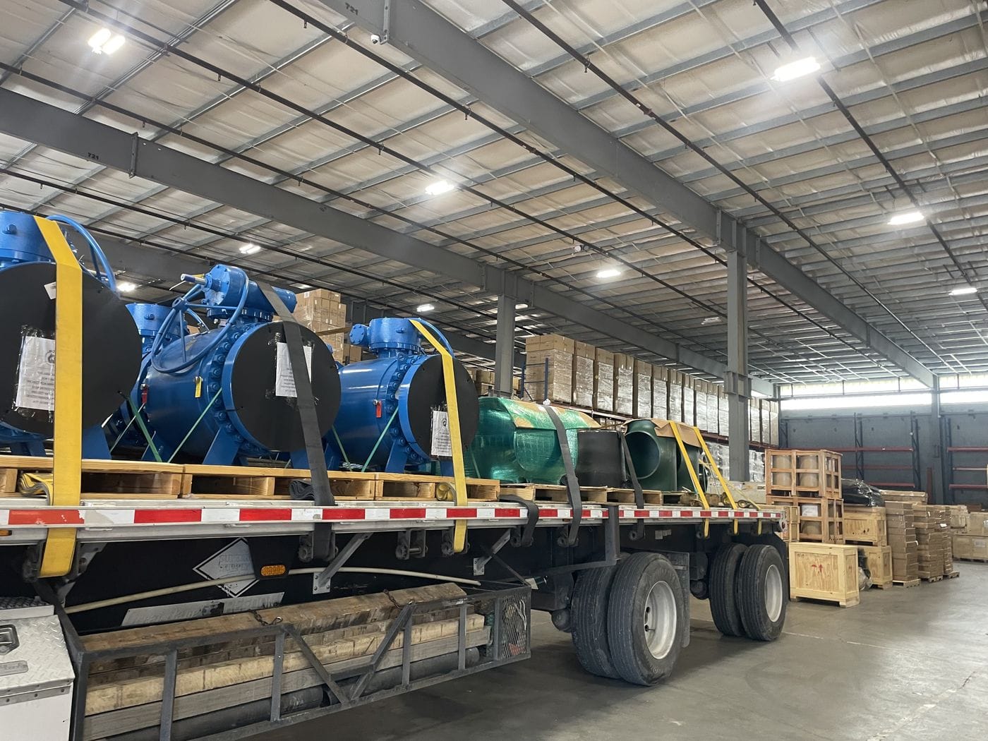 Flatbed trailer hauling industrial equipment at a warehouse dock